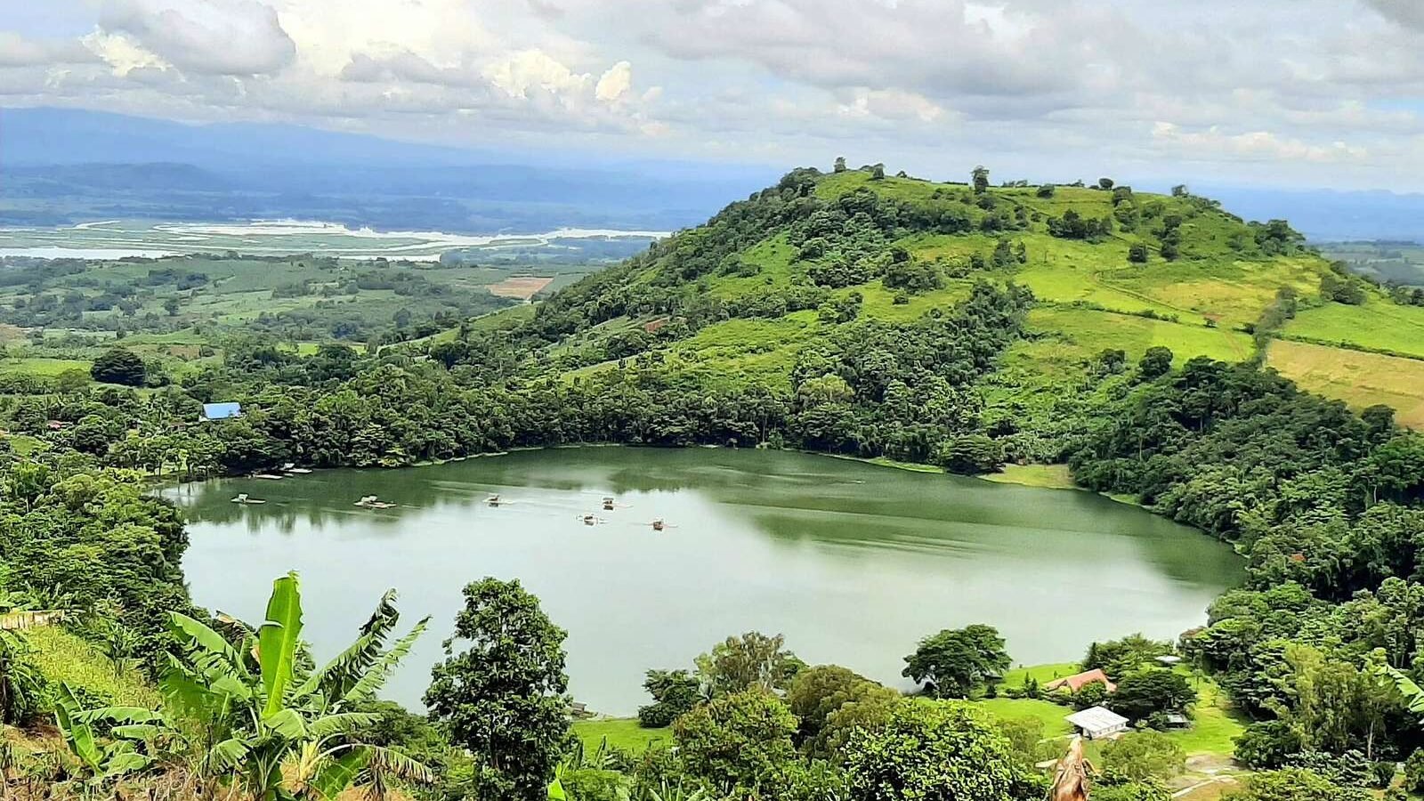 The crater lake of Lake Apo ringed by green hills in Valencia, Bukidnon, Philippines