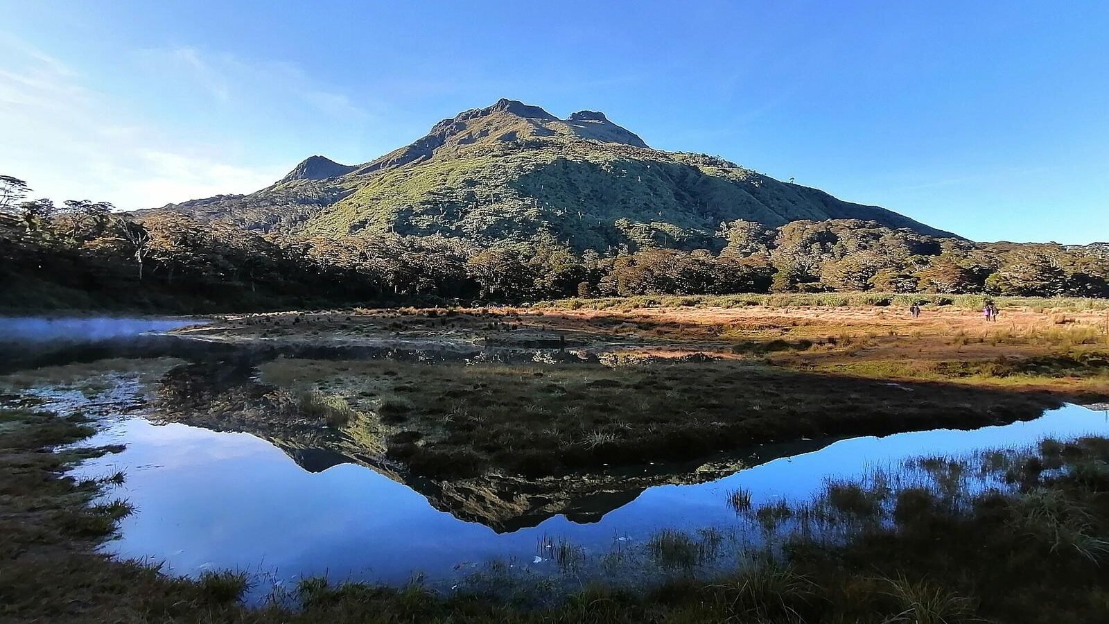 The summit of Mount Apo reflected in a tarn under a clear sky, the highest mountain in the Philippines