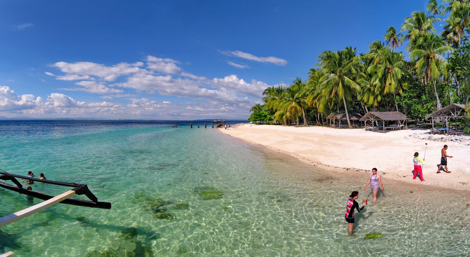 White sand beach fringed with coconut palms and clear shallow water on Samal Island, Davao, Philippines