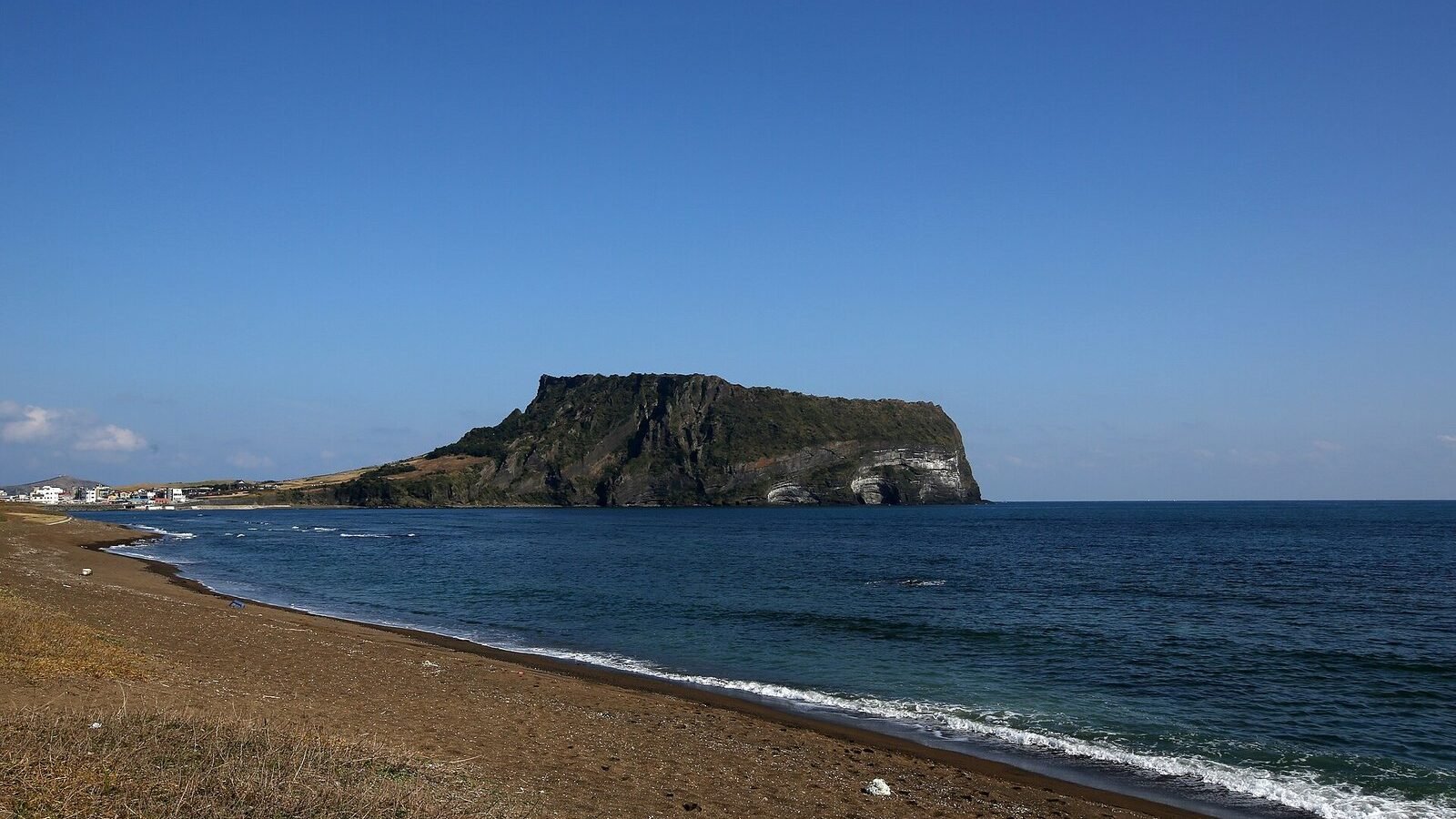 The Seongsan Ilchulbong tuff cone rising from the sea, seen from the shore on Jeju Island, South Korea