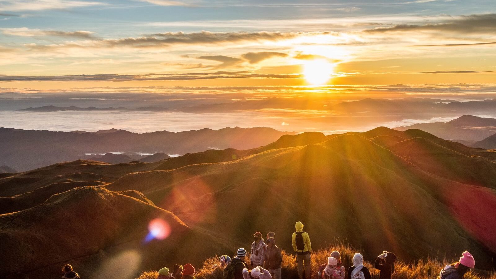Hikers watching sunrise above the sea of clouds from the summit of Mount Pulag, Benguet, Philippines