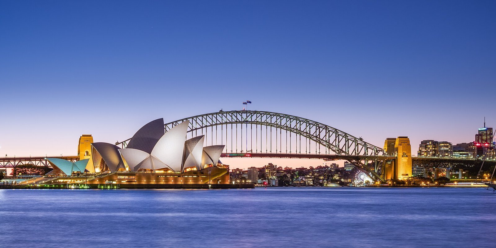 The Sydney Opera House and the Sydney Harbour Bridge at dusk across the harbour in Sydney, Australia